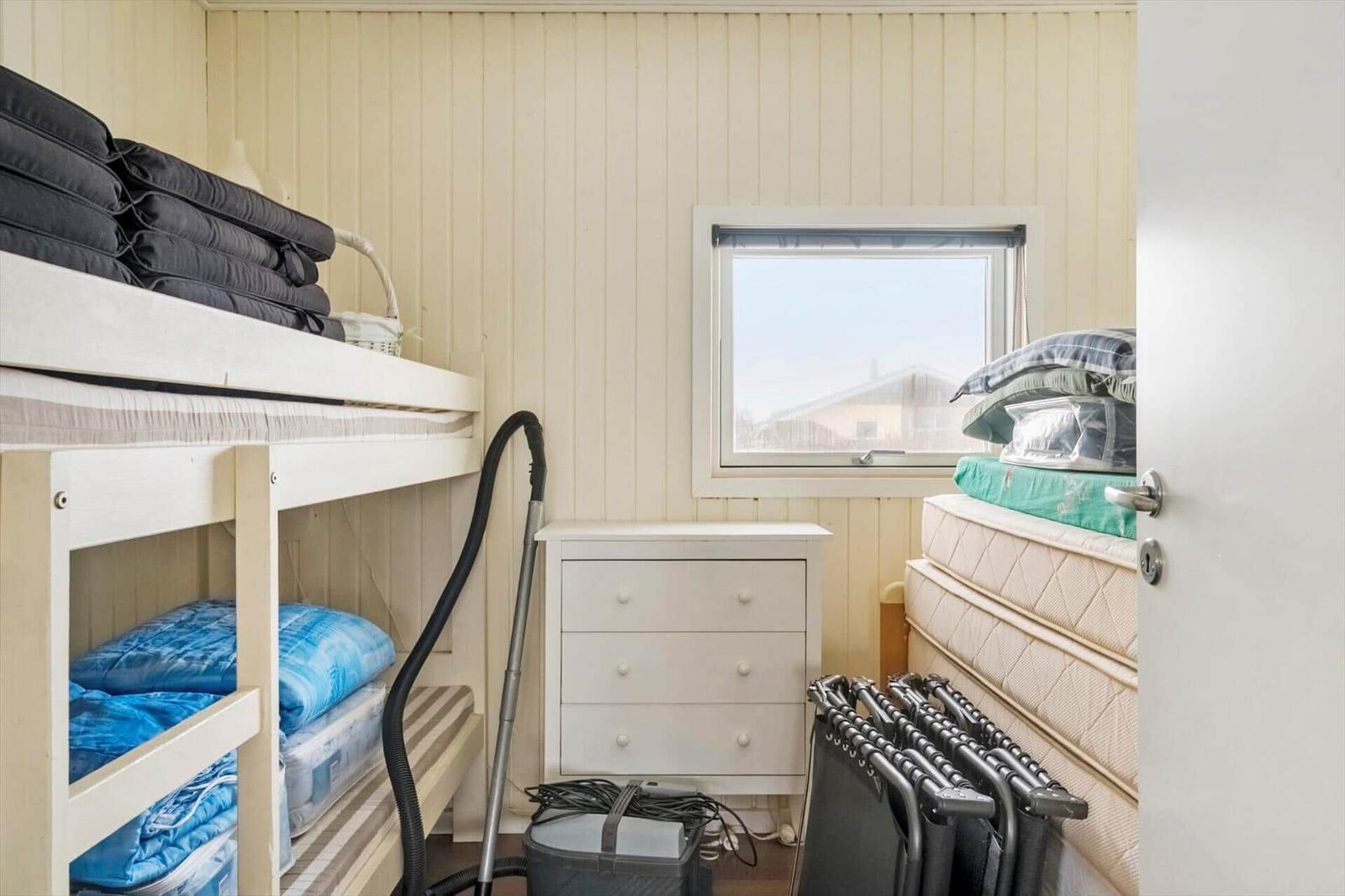 Kleines Schlafzimmer mit Doppelstockbett, Schrank und Fenster.