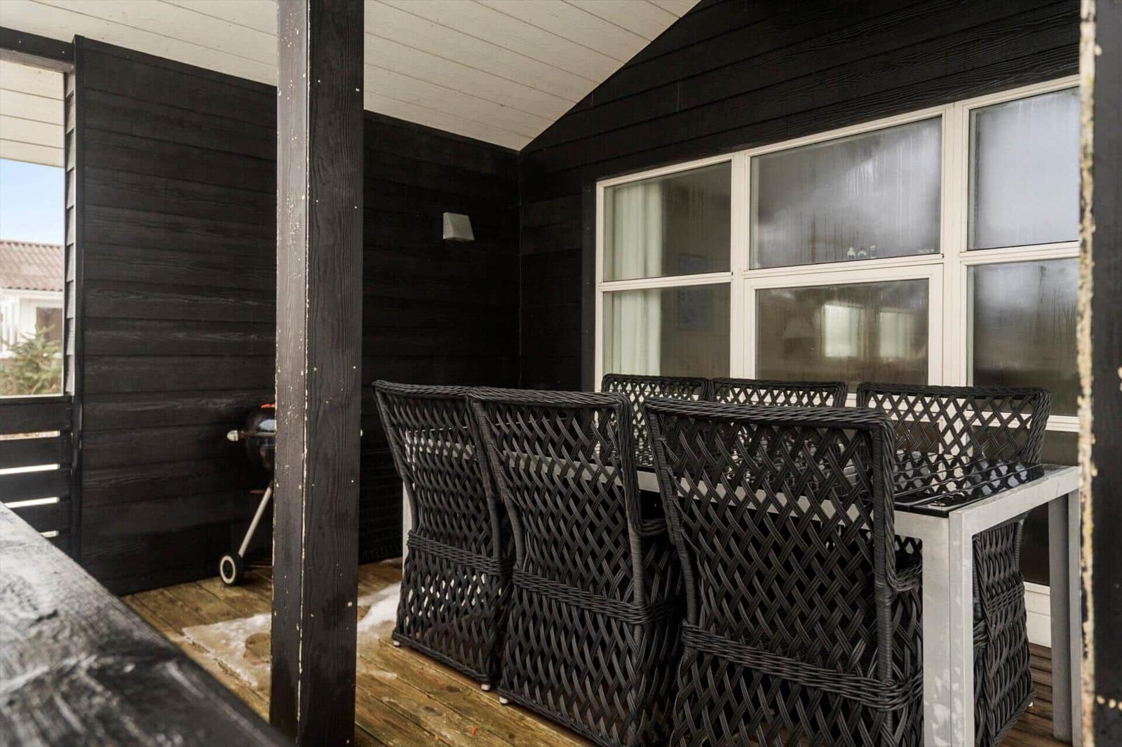 Terrasse mit Tisch und Stühlen, Grill und Fenster zur Wohnung.