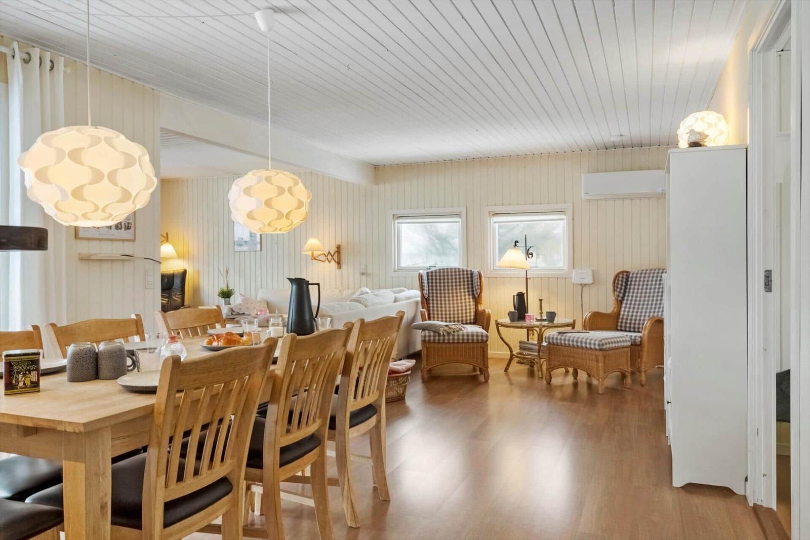 Esszimmer mit Holztisch und Stühlen. Wohnbereich mit Sitzgruppe und Fenstern.