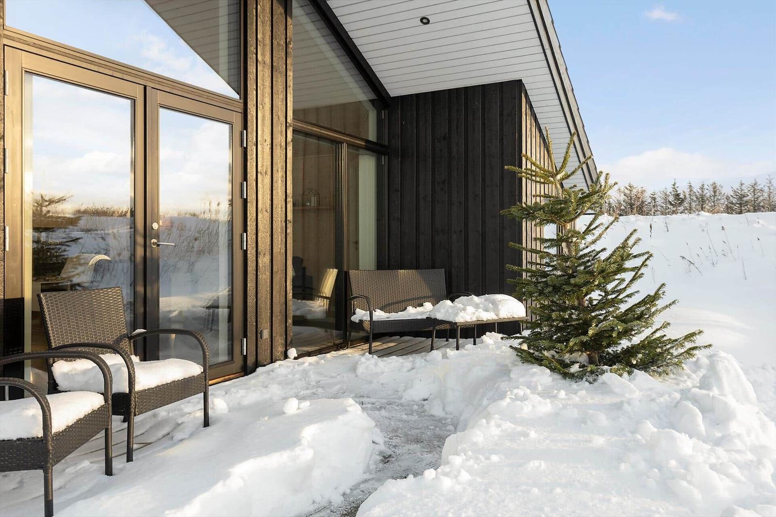 Winter terrace with seating and snow cover in front of modern house.