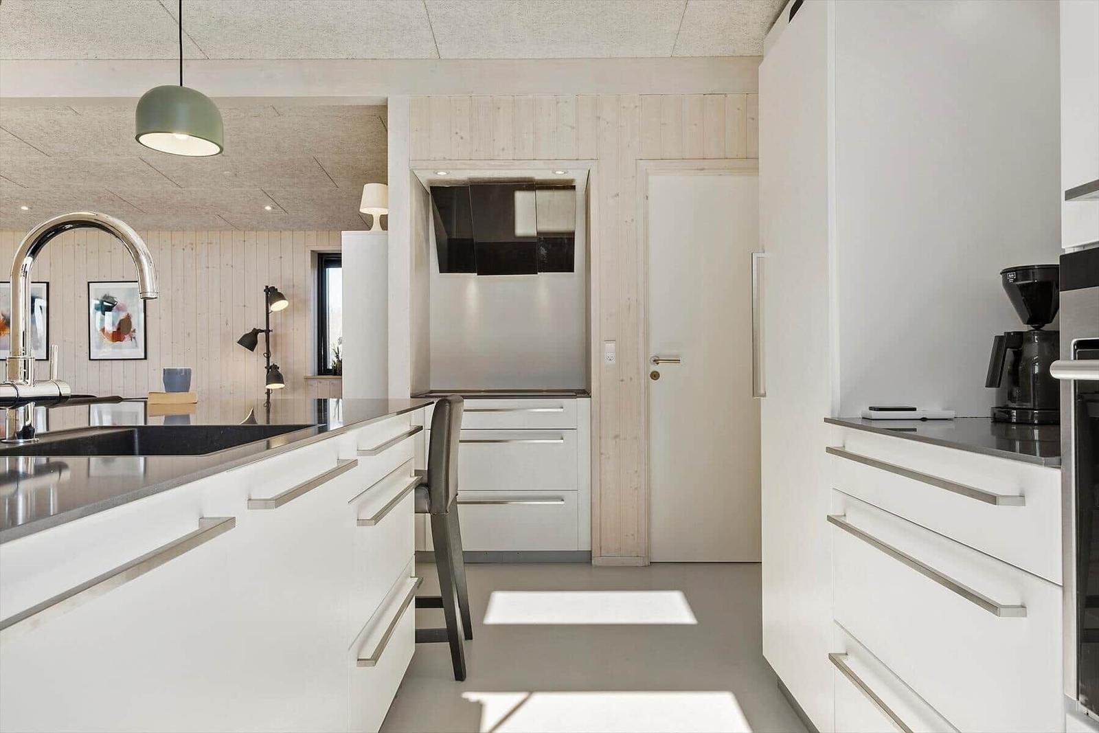 Moderne Küche mit weißen Schränken, schwarzer Arbeitsplatte und Edelstahlspüle.