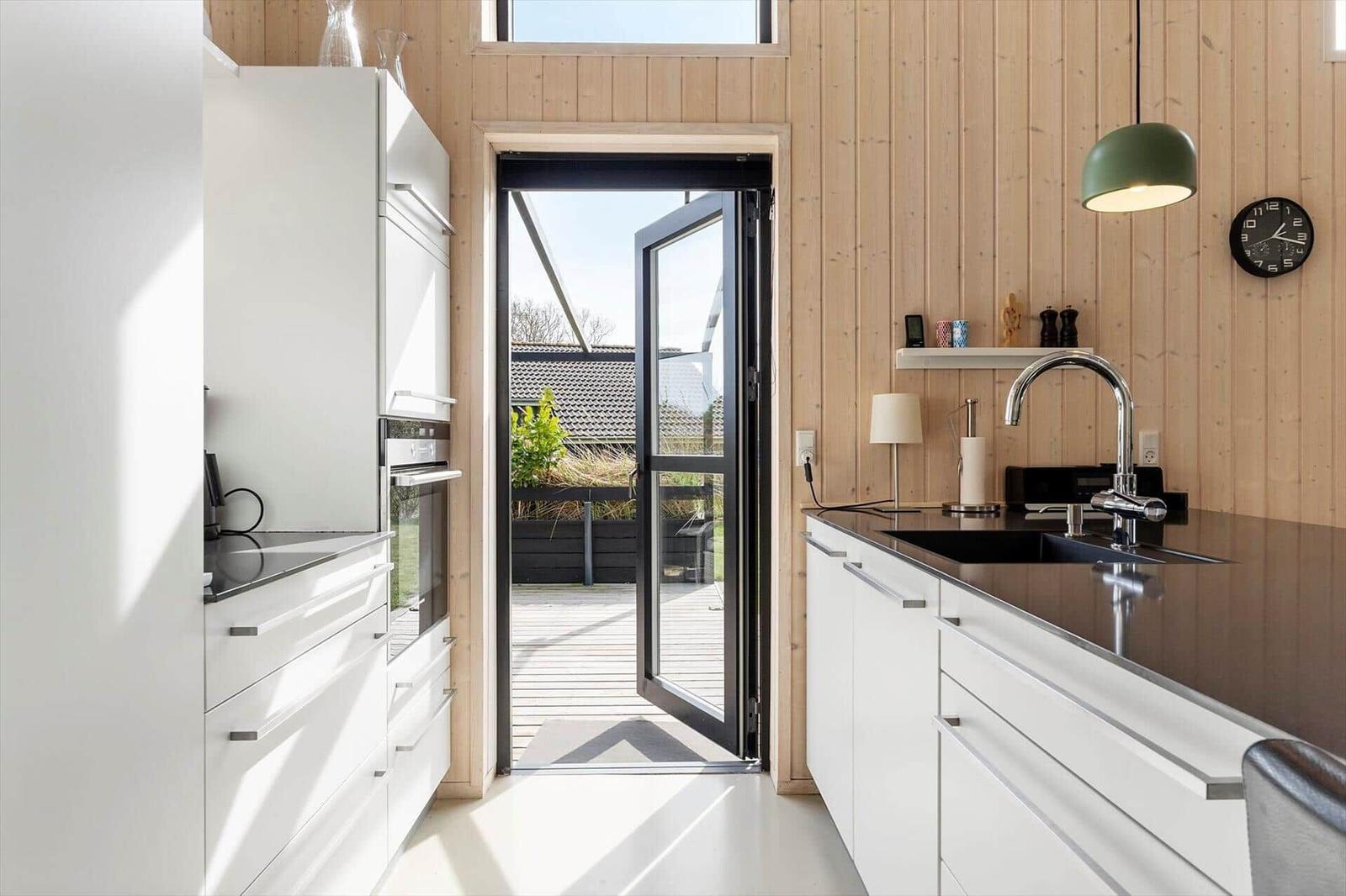 Moderne Küche mit weißen Schränken und Blick auf die Terrasse.