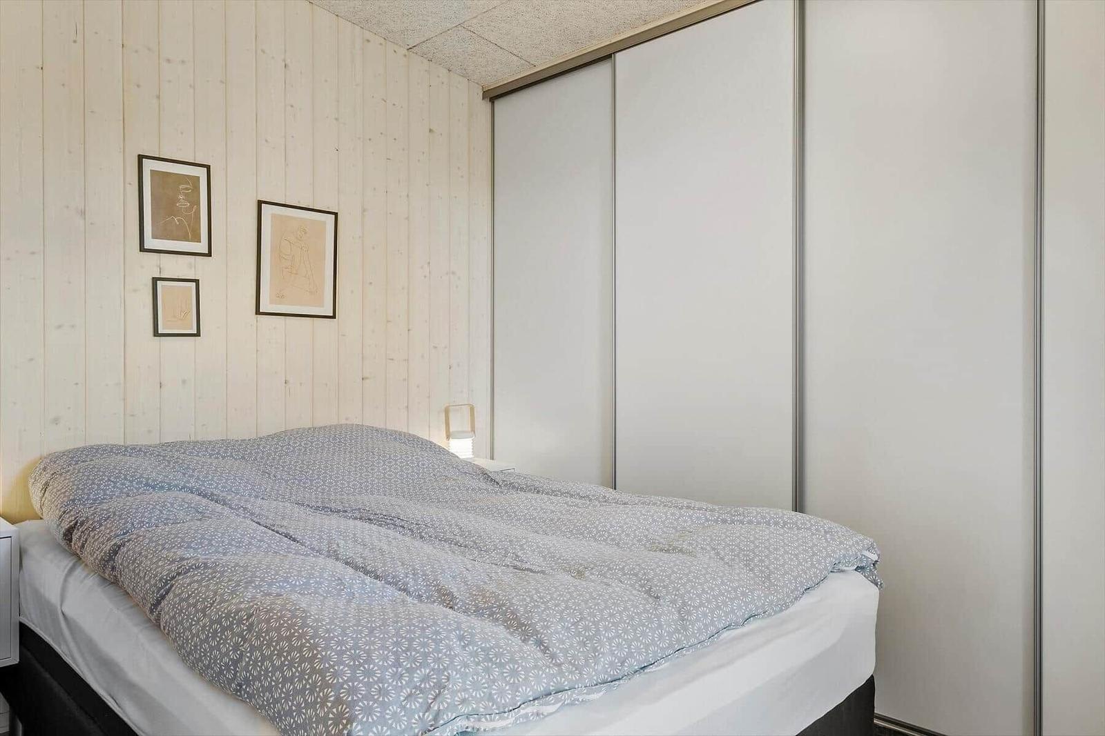 Schlafzimmer mit Bett, Kleiderschrank und Holzwand
