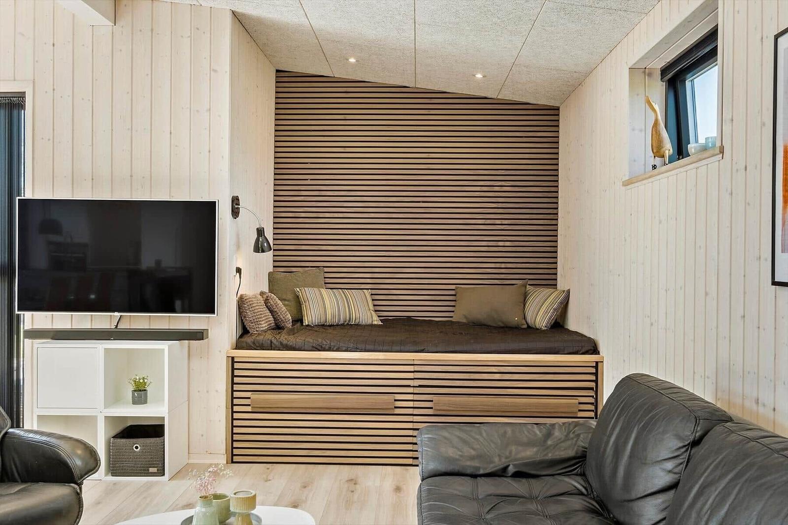 Wohnzimmer mit Schlafcouch, Fernseher und Ledersofa.
