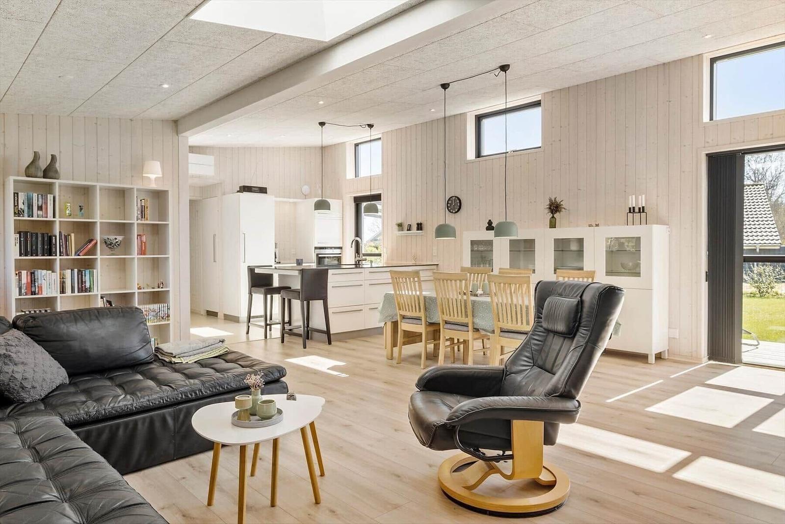 Wohnbereich mit Ledersofa, Essbereich und Küche. Holzboden und helle Wände.