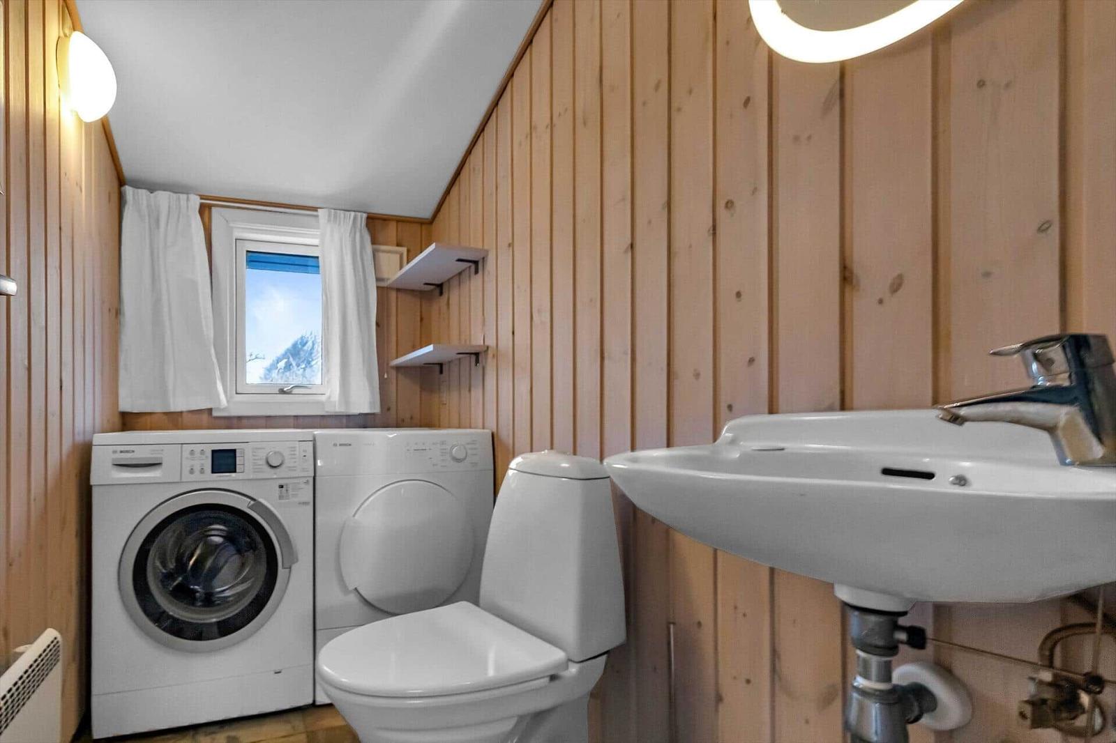 Badezimmer mit Waschmaschine, Trockner, Toilette und Waschbecken.