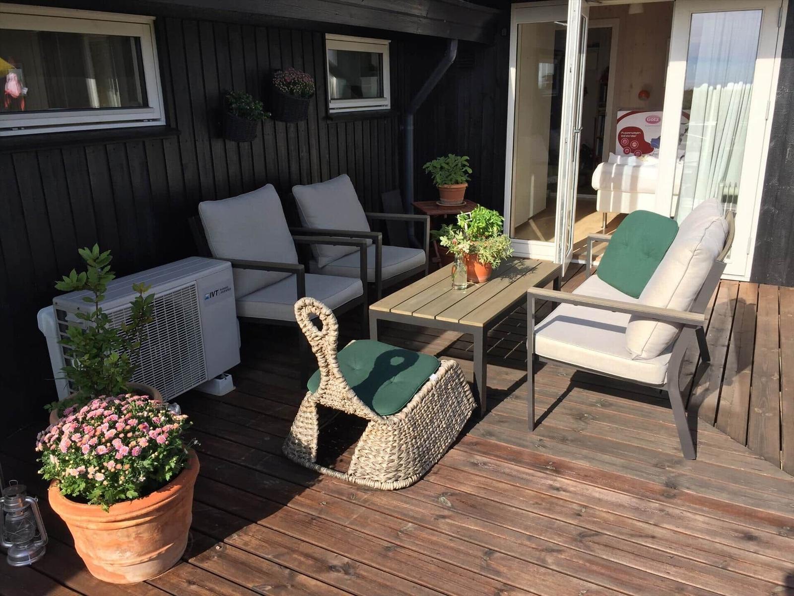 Terrasse mit Sitzgruppe, Tisch und Pflanzen. Durchgang ins Innere.