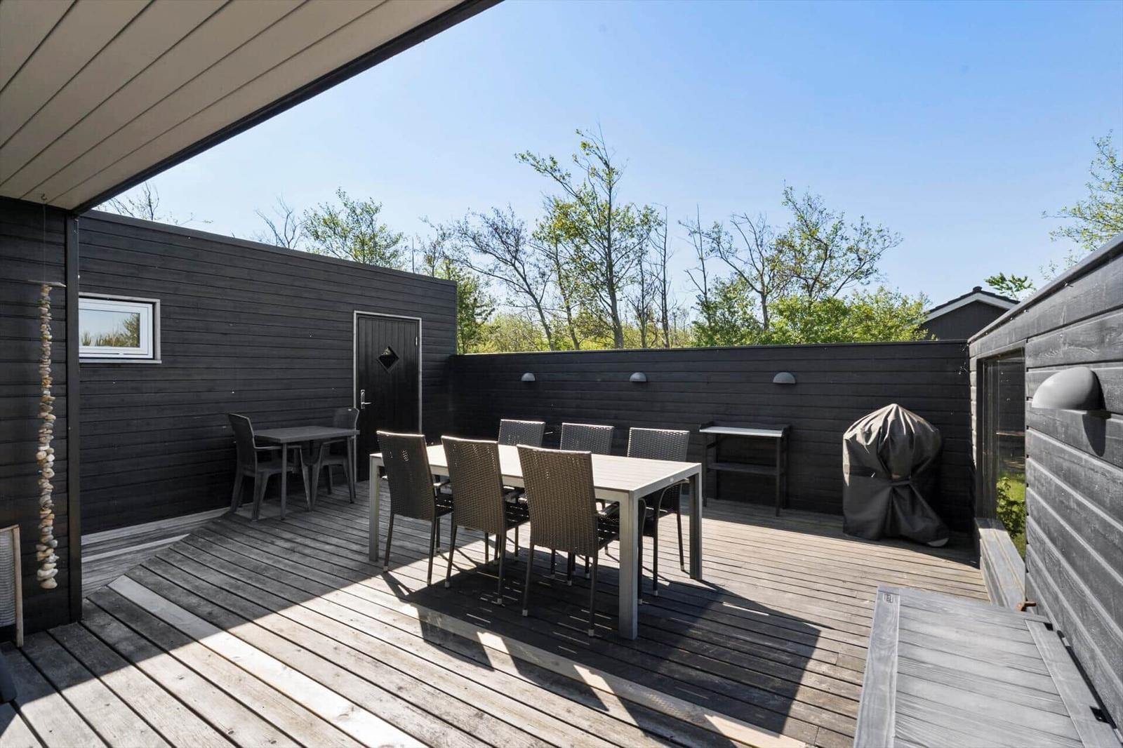 Deck with table, chairs, and grill under open sky.
