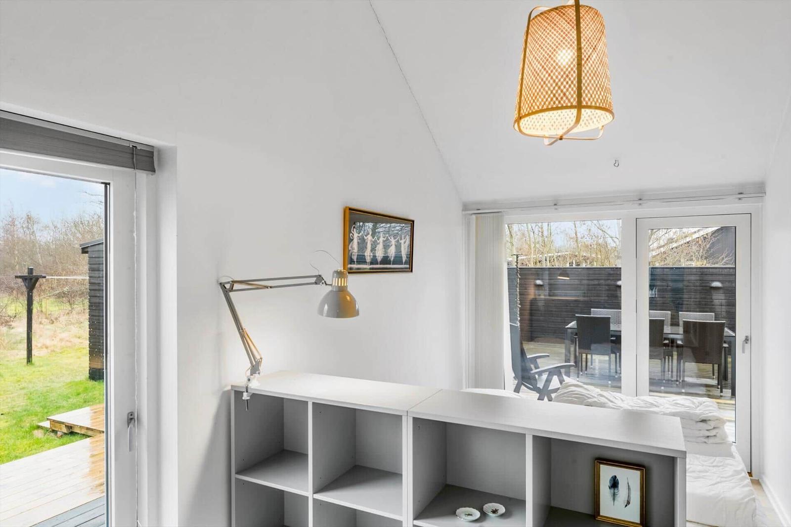 Room with white walls, desk, bed, and windows to the terrace.