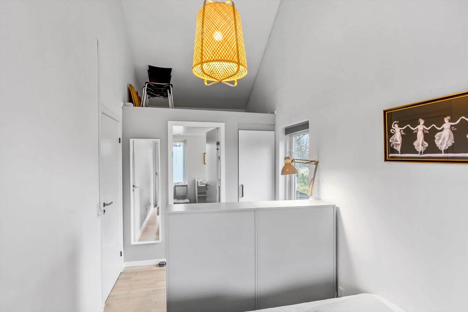 Bedroom with white walls, a ceiling lamp, and a picture on the wall.
