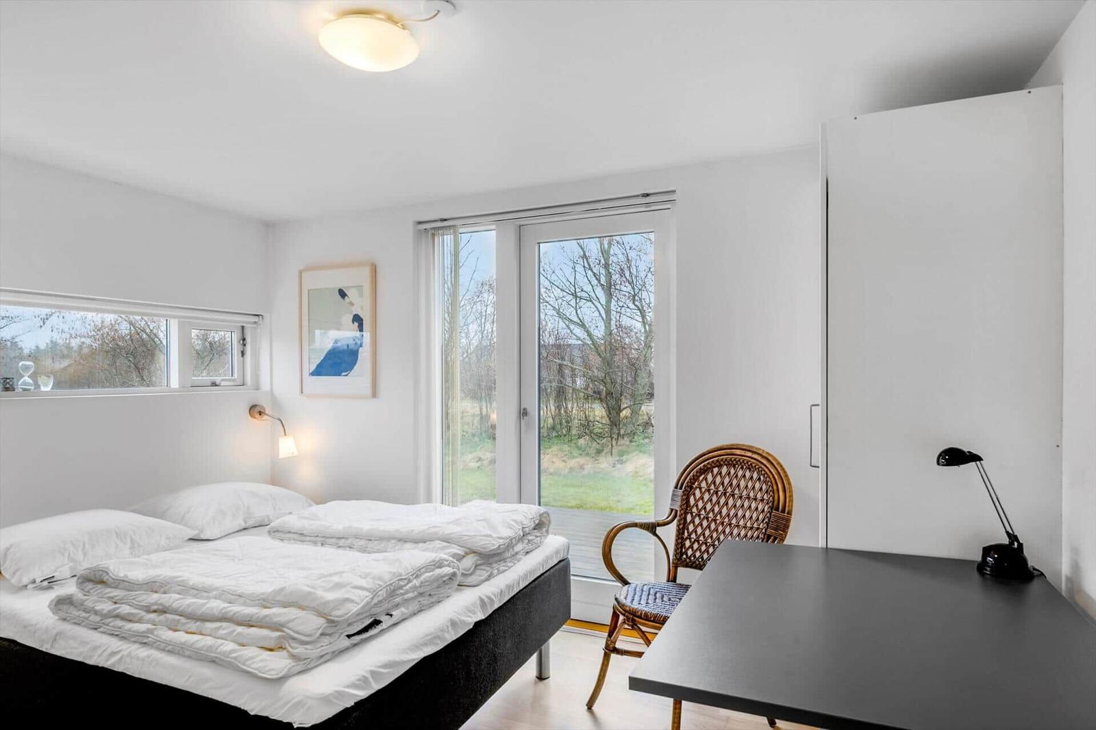 Bedroom with bed, desk, chair, and window with view.
