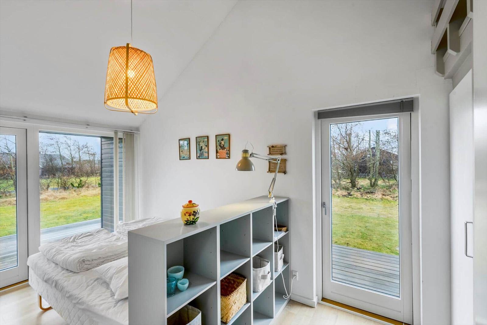 Bedroom with bed, shelving unit, and windows to outdoor terrace.