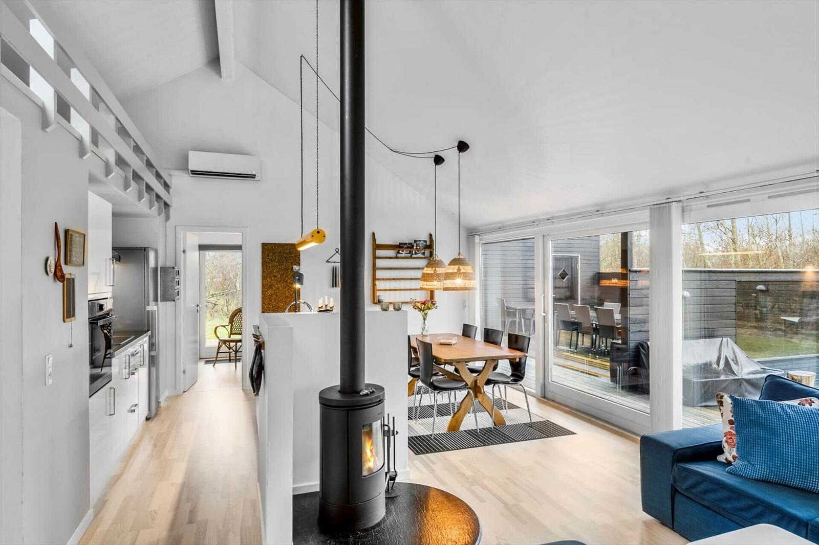 Modern open kitchen, dining area, and living room with fireplace and large window area.