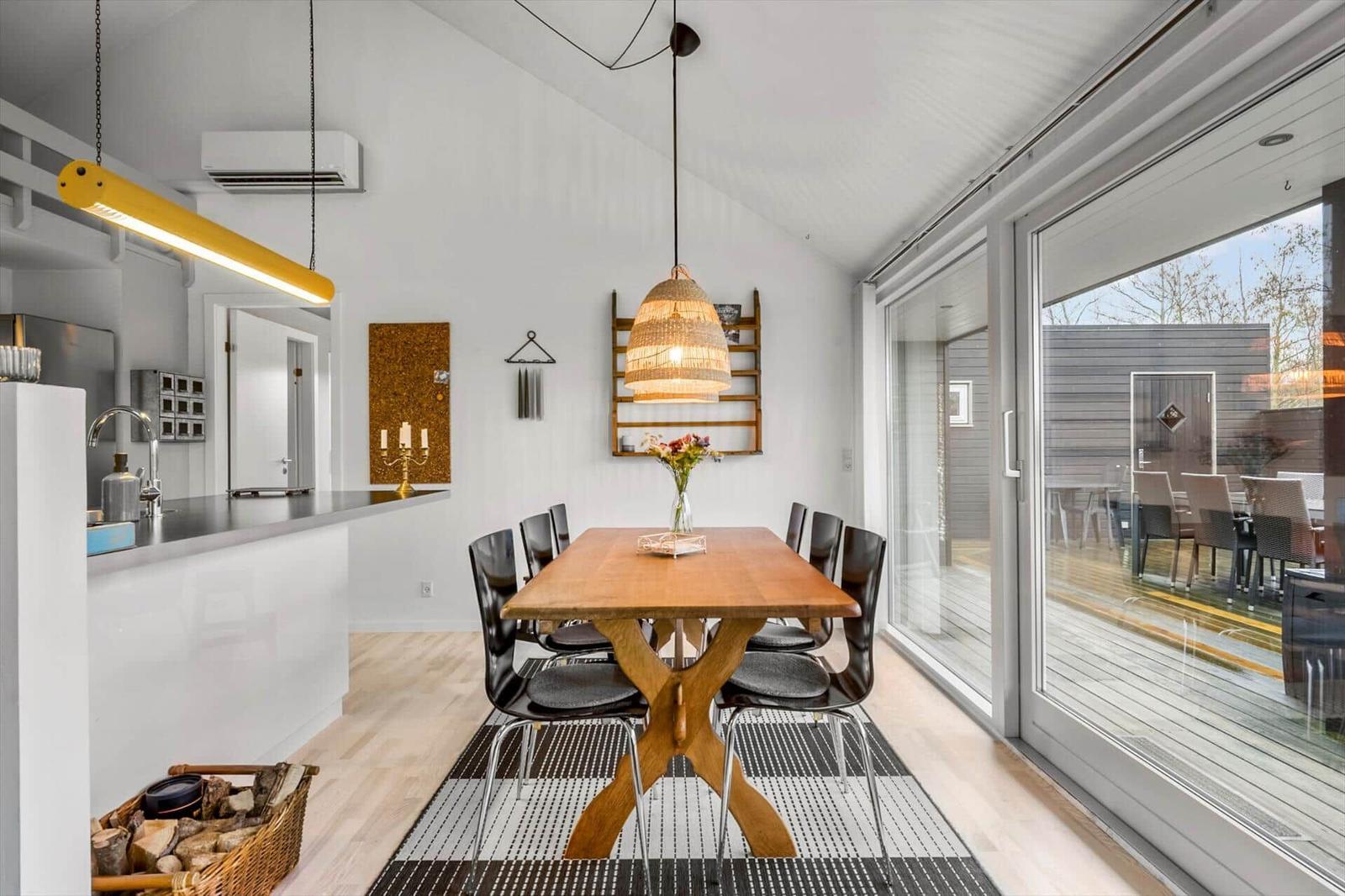 Dining room with wooden table, black chairs, and glass door to terrace.