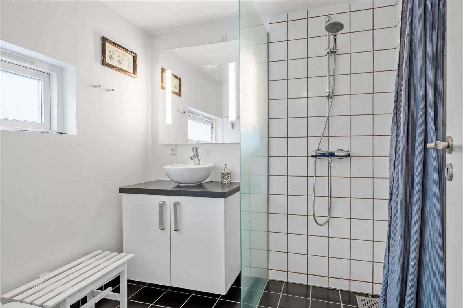 Bathroom with shower, sink and window. Tiles and white walls.