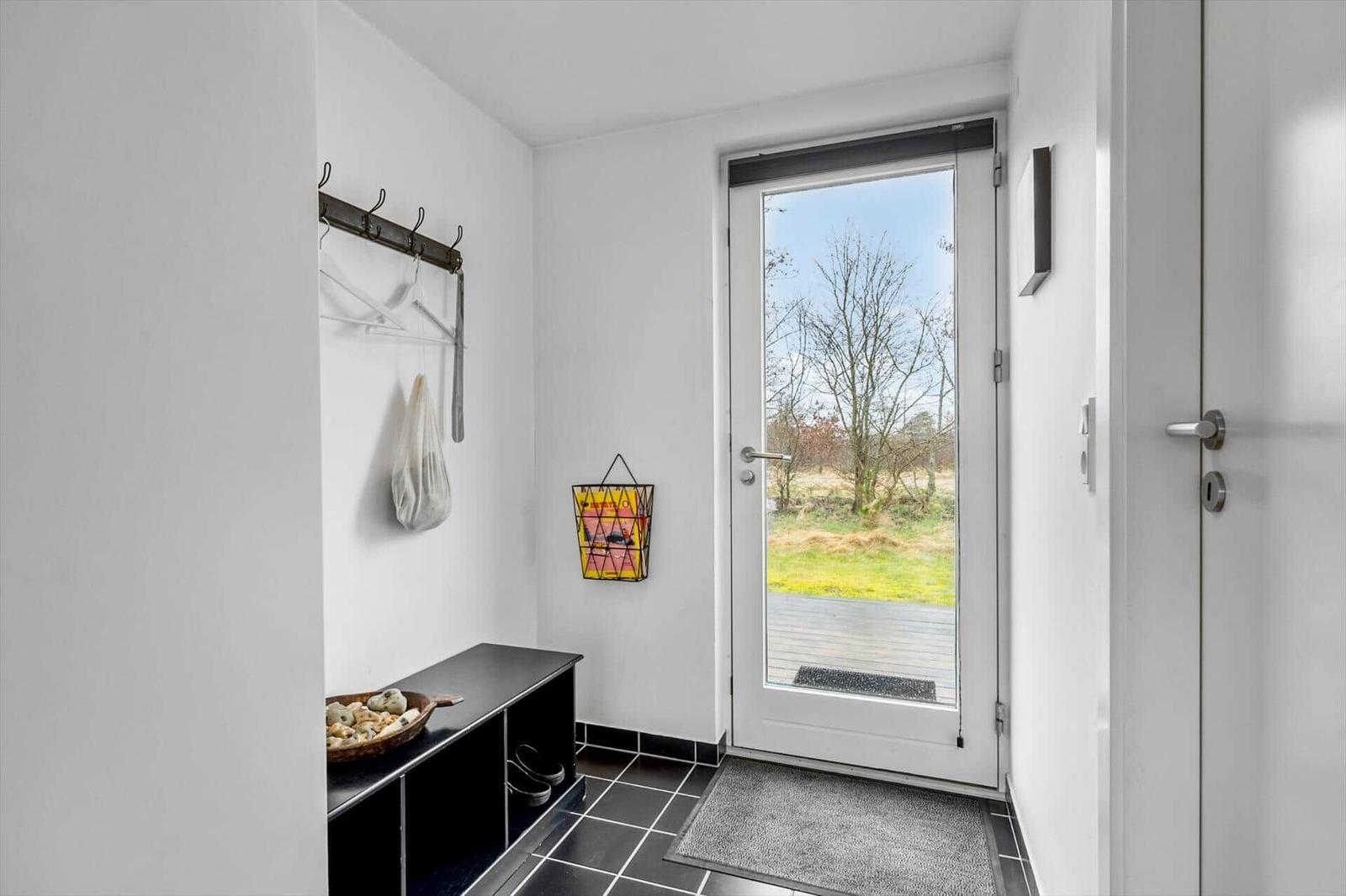 Entrance area with shoe cabinet, hooks, and glass door to the outside.