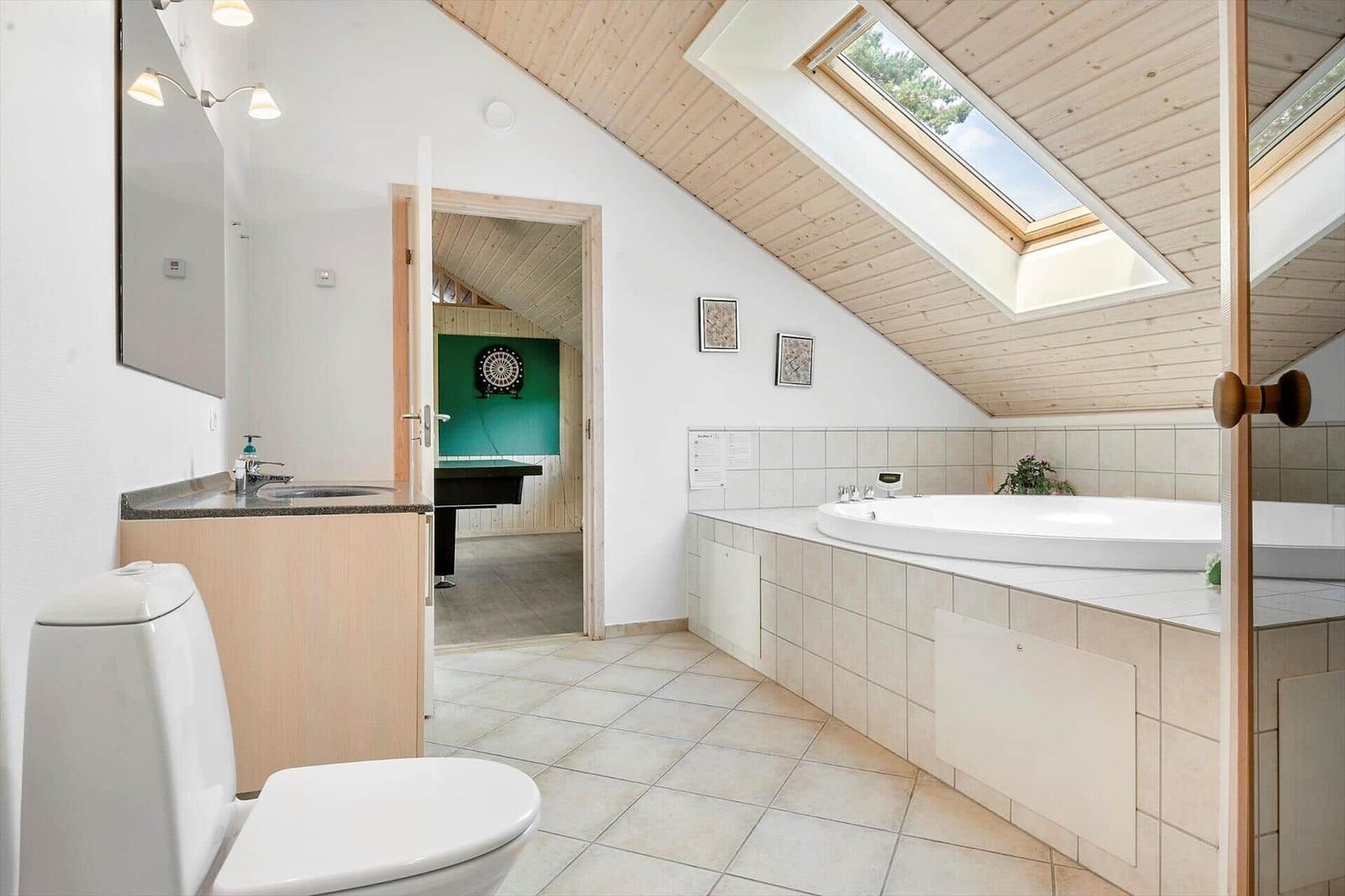 Bathroom with whirlpool, toilet, and sink. Passage to a dart room.