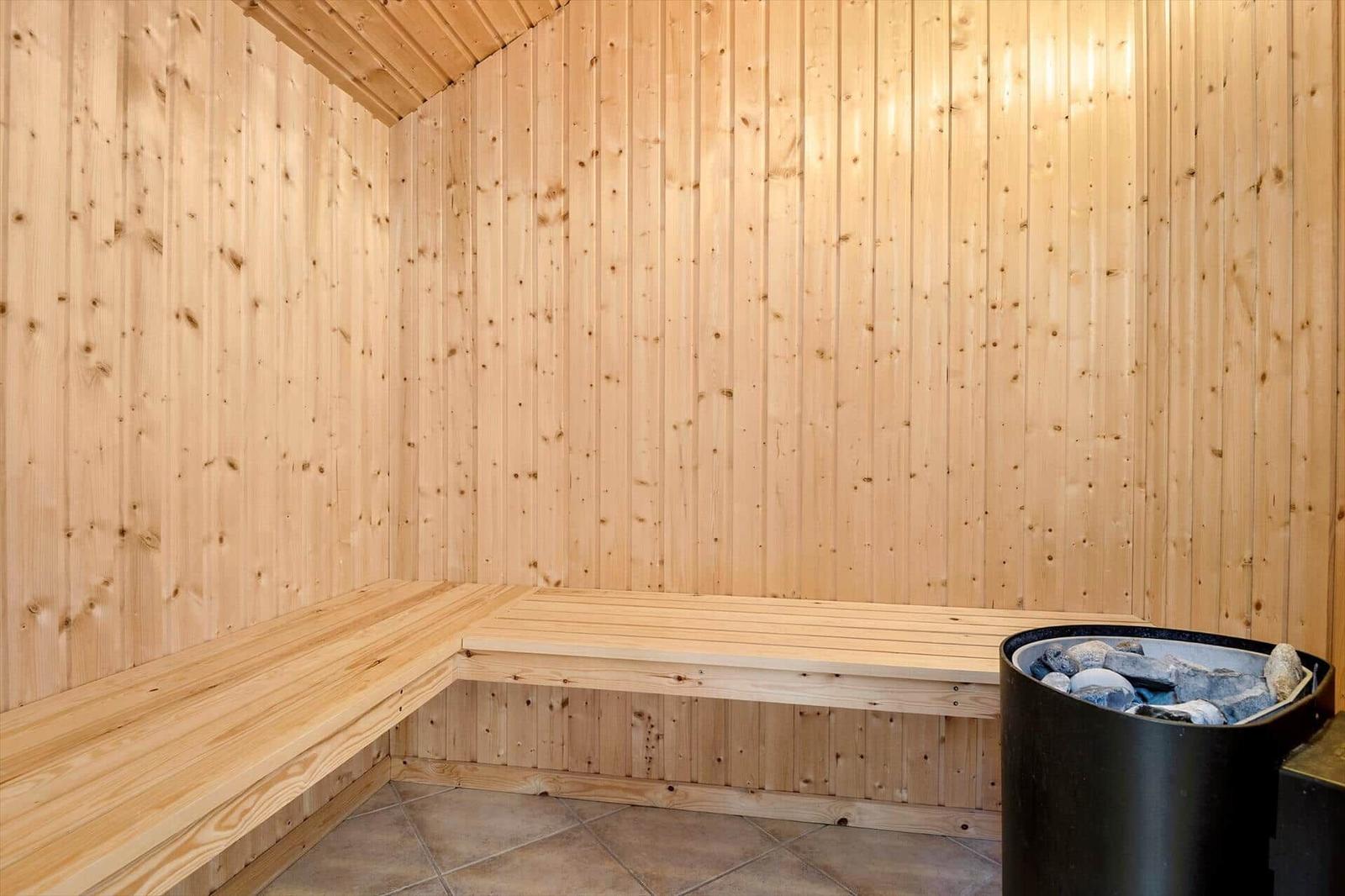 Sauna with wooden walls and bench. Stones in the heater.