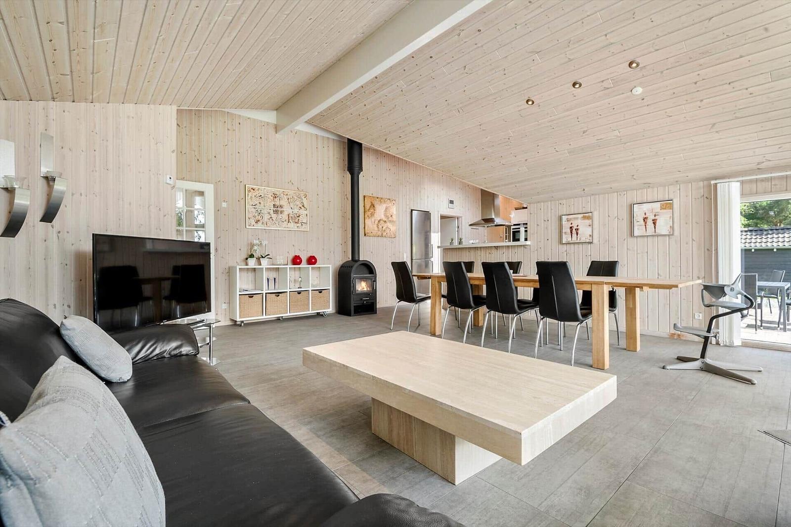 Living and dining area with wood walls, fireplace, dining table, and sofa.