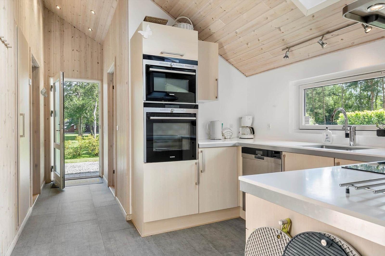 Kitchen with wood walls, built-in appliances, and view of the garden.