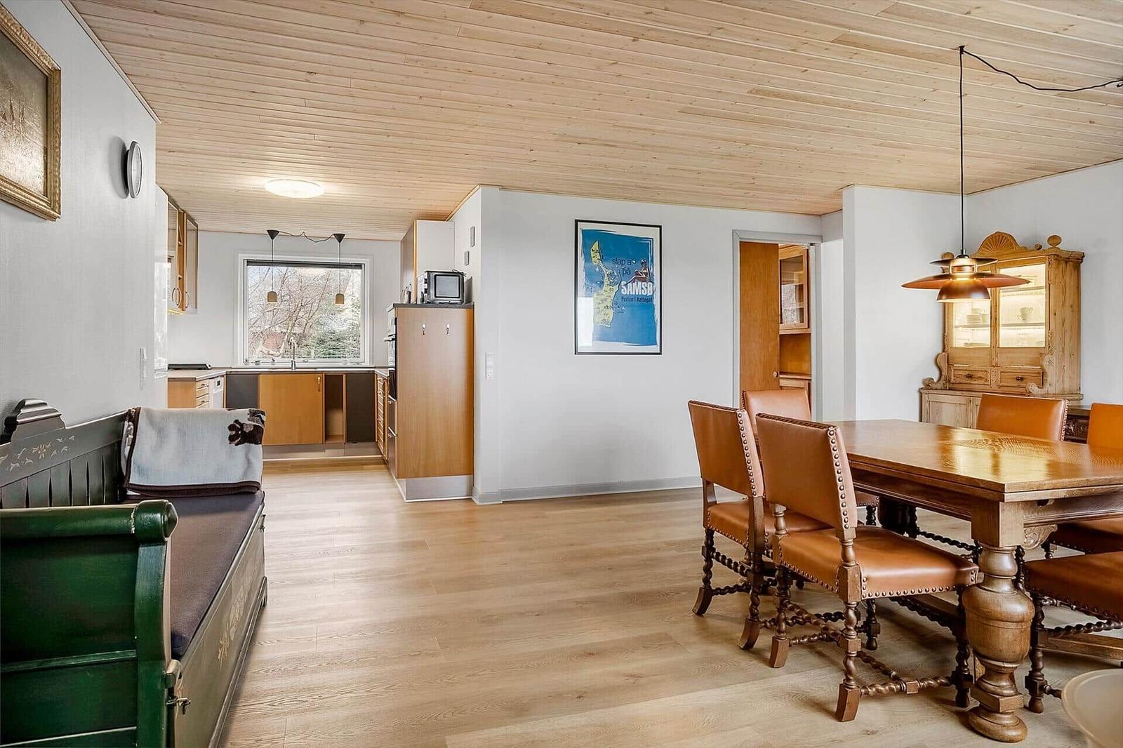 Ein Raum mit Essbereich, Küchenzeile und grünem Sofa. Holzdecke und Boden.