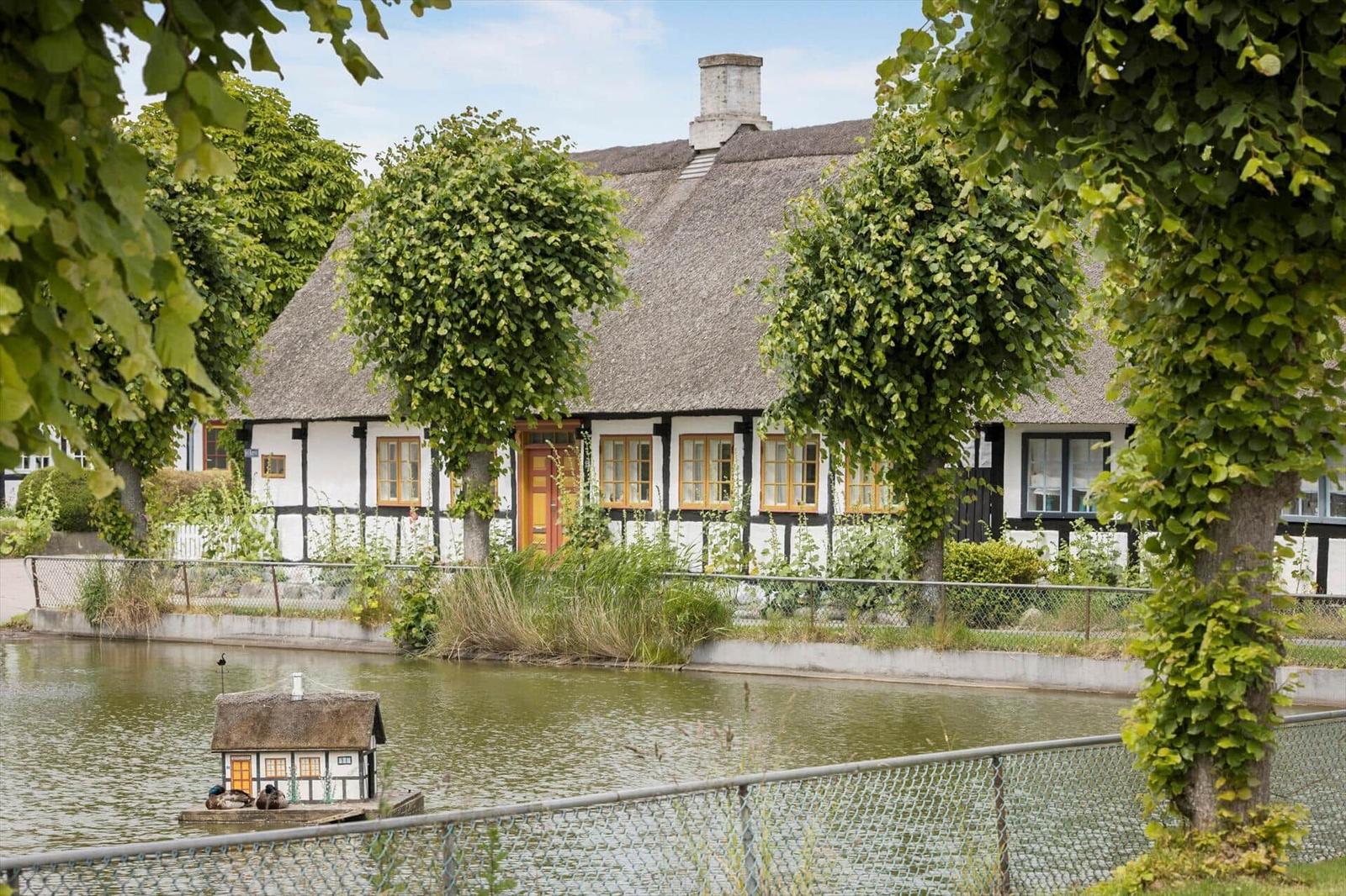 Haus mit Strohdach und gelber Tür am Wasser