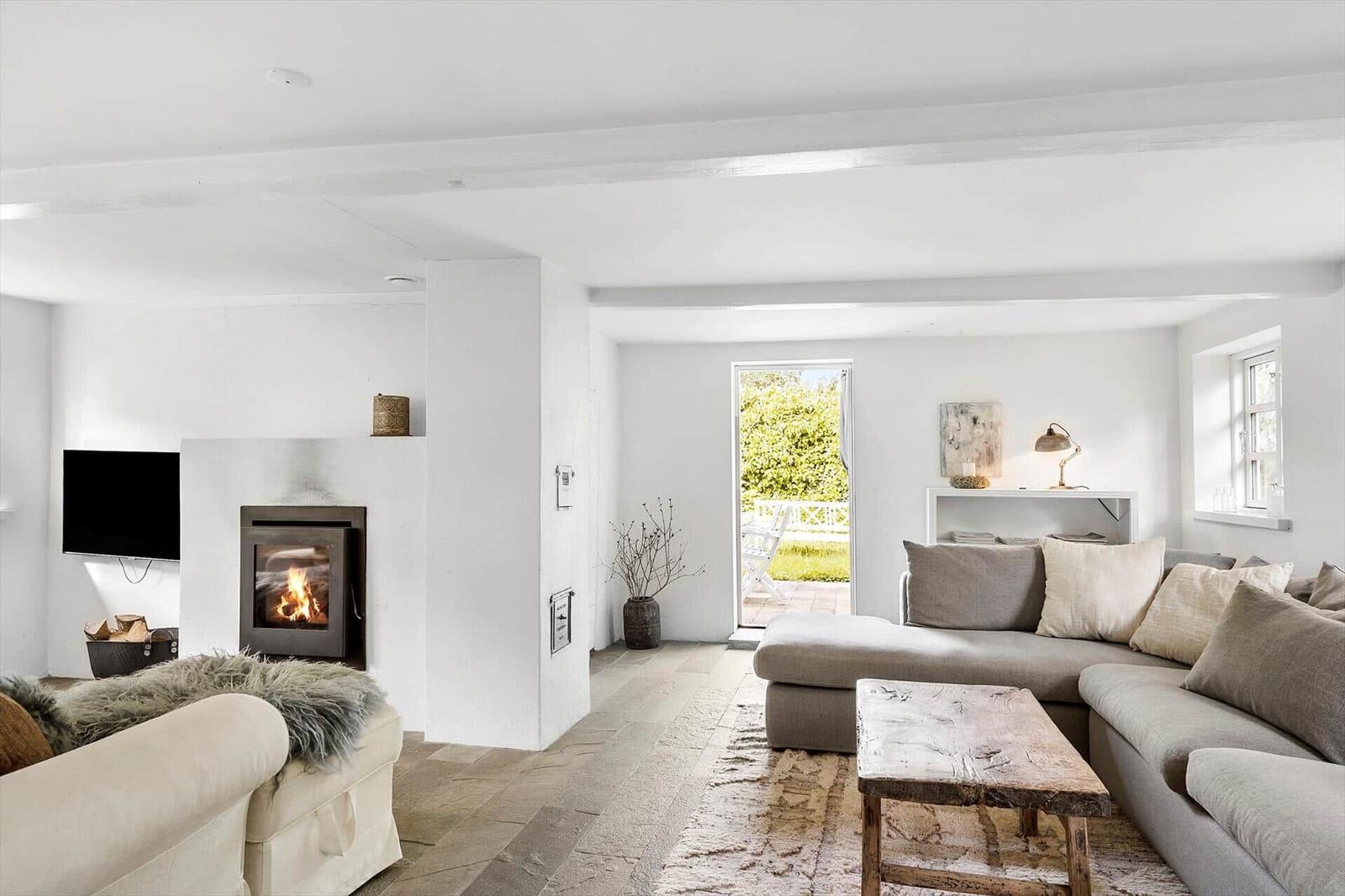 Wohnzimmer mit Kamin, Sofa und Blick auf Garten.