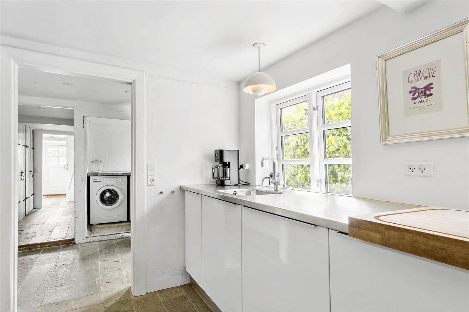 Küche mit Waschmaschine im Anschluss, Fenster und Bild an der Wand.