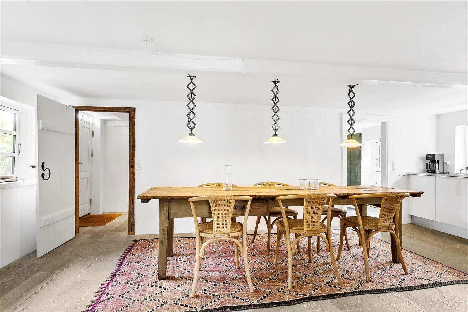 Esszimmer mit Holztisch, Stühlen und Deckenleuchten auf Teppich