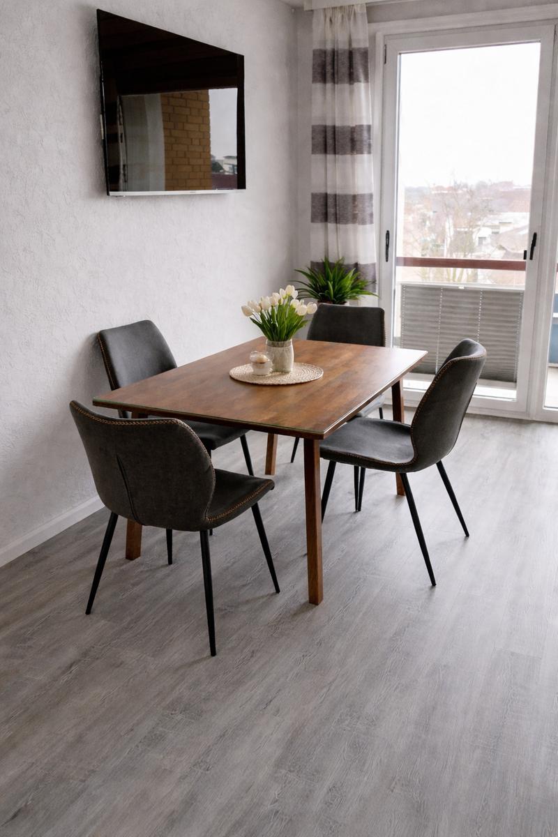 Essbereich mit Holztisch, vier Stühlen und Blick auf Balkon