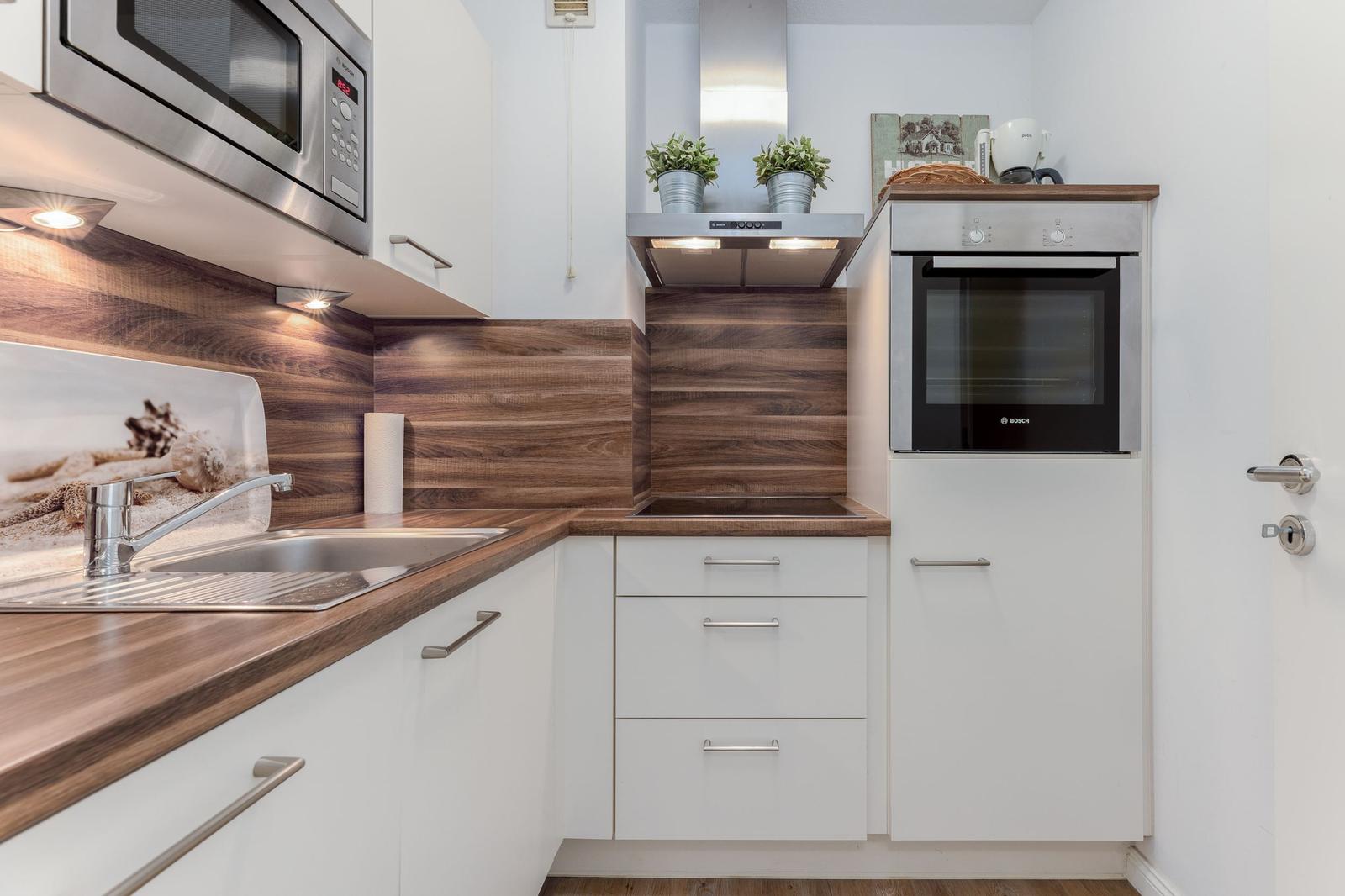 Küche mit Edelstahlgeräten, Holzoberflächen und integriertem Backofen.