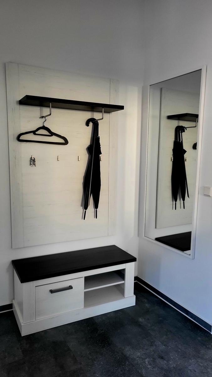 Eingangsbereich mit Garderobe, Spiegel und Bank.