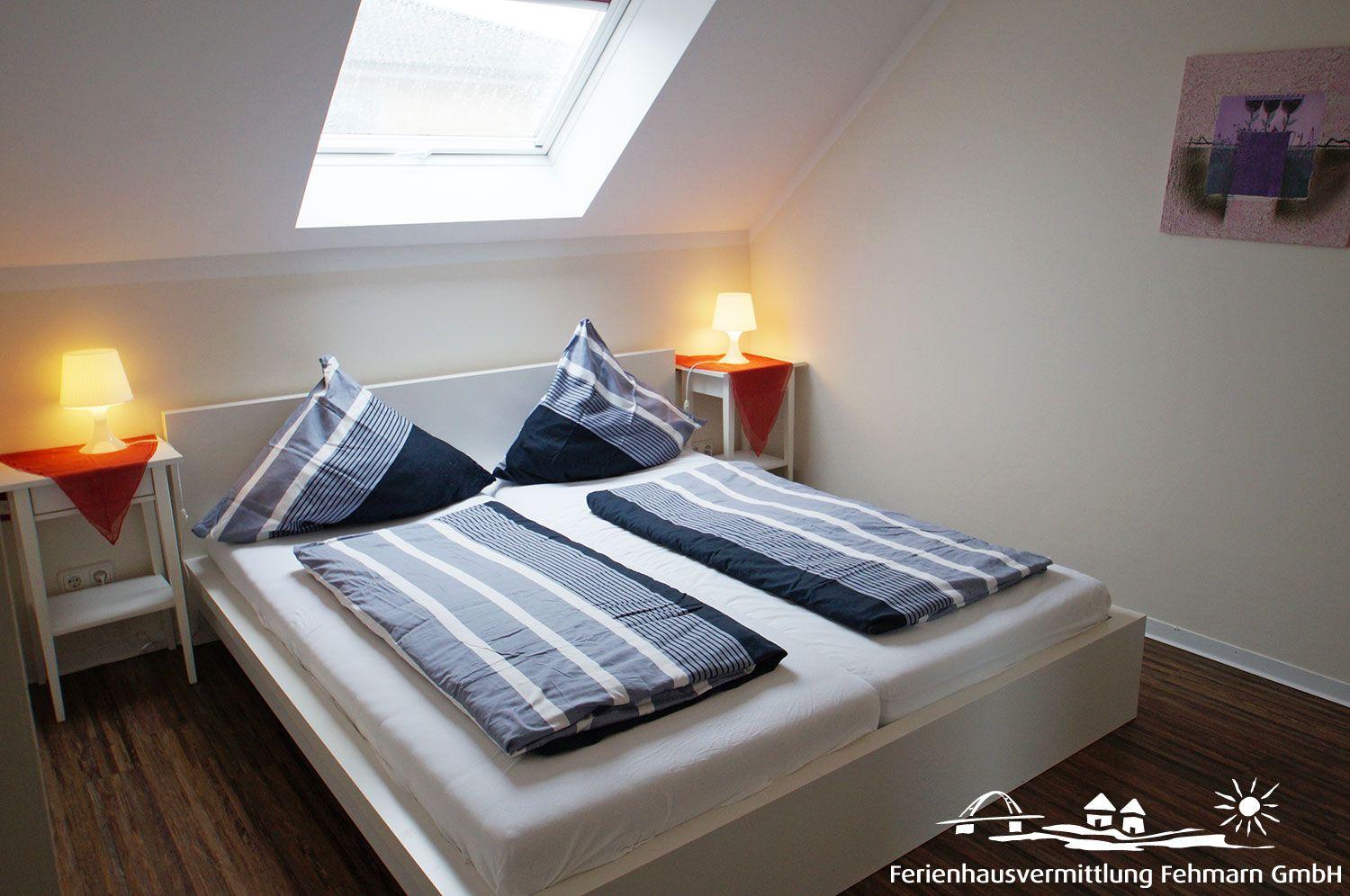 Bedroom with sloped ceiling, skylight, bed, and two nightstands with lamps.