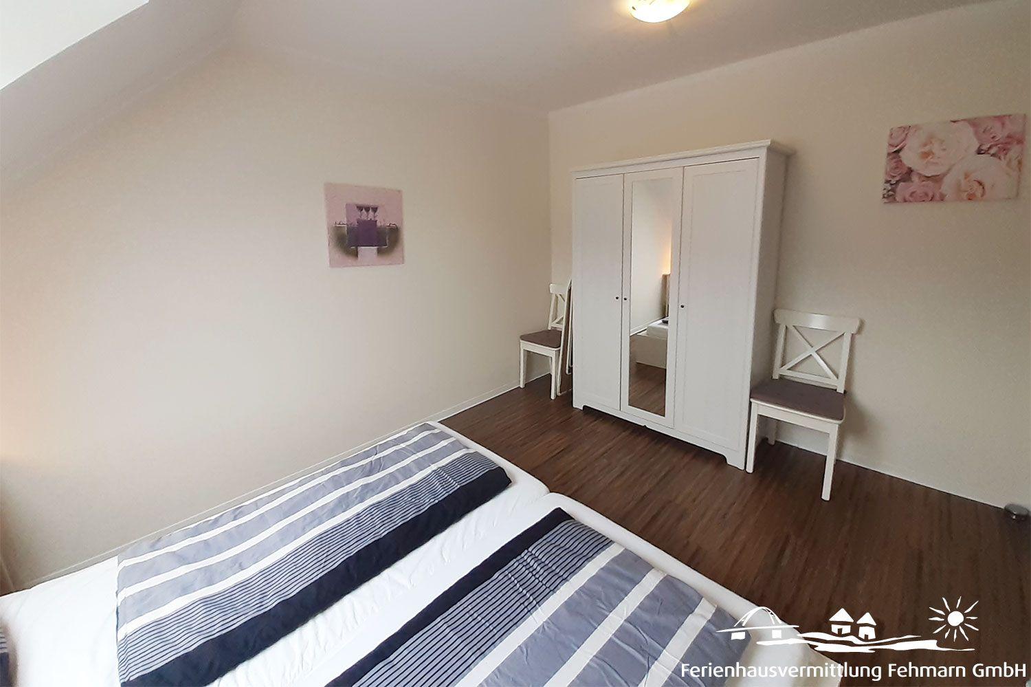 Bedroom with double bed, wardrobe, and two chairs.