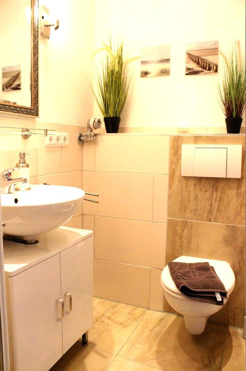 Badezimmer mit Waschbecken, Toilette und Pflanzen an der Wand.