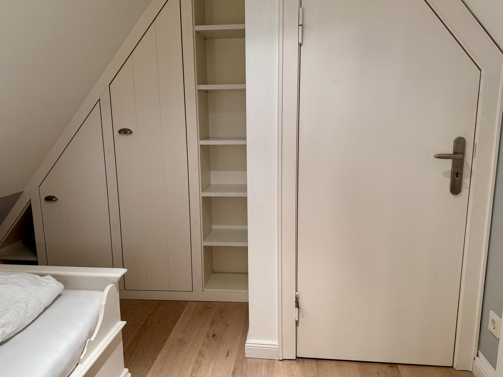 Schlafzimmer mit weißen Schränken und Holzboden