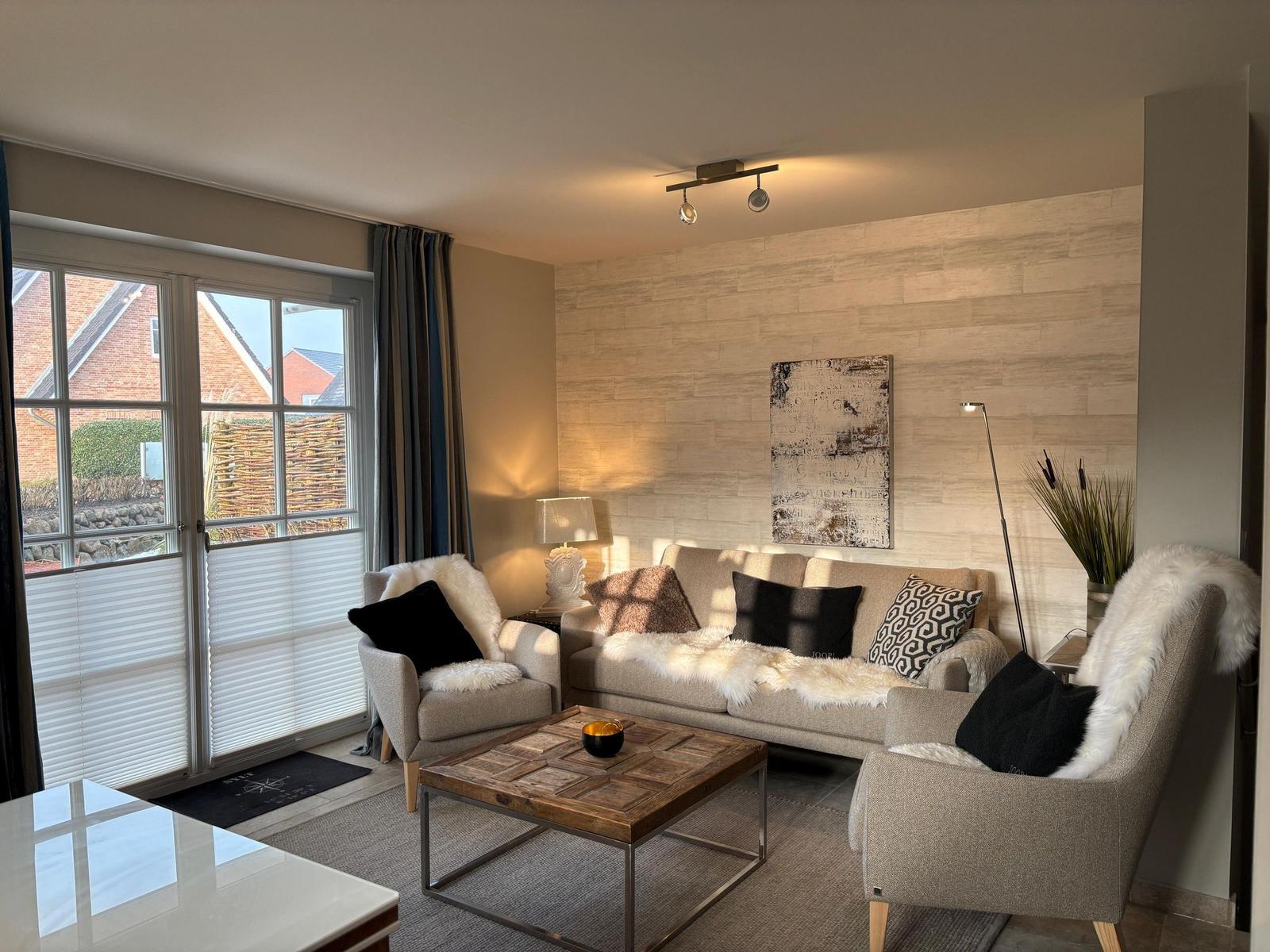Living room with sofa, two chairs, and wooden table. Doorway to outdoor area.