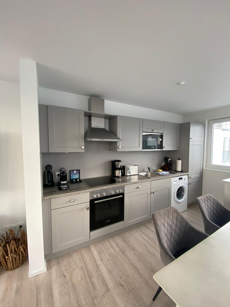 Modern kitchen with gray cabinets, cooktop, and washing machine.
