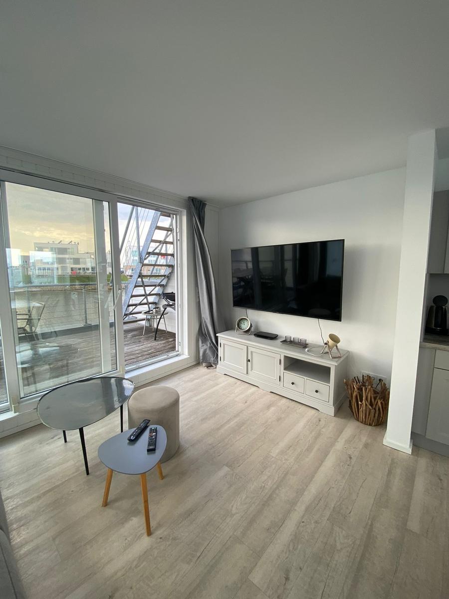 Living room with TV, terrace and wooden floor. Modern furniture and large windows.