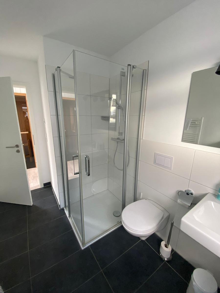 Bathroom with shower, toilet, and sink. Tile floor and mirror.