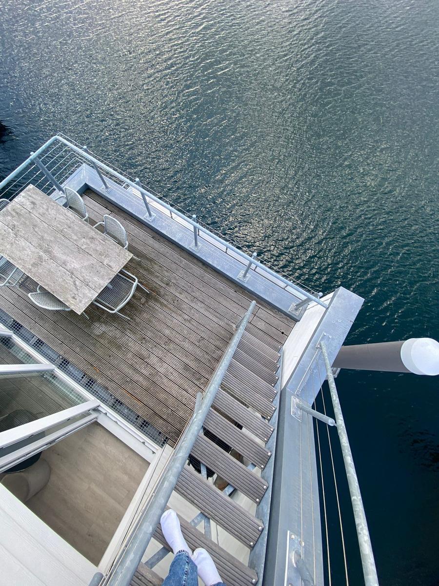 Deck with table and chairs over water, access via wooden steps.