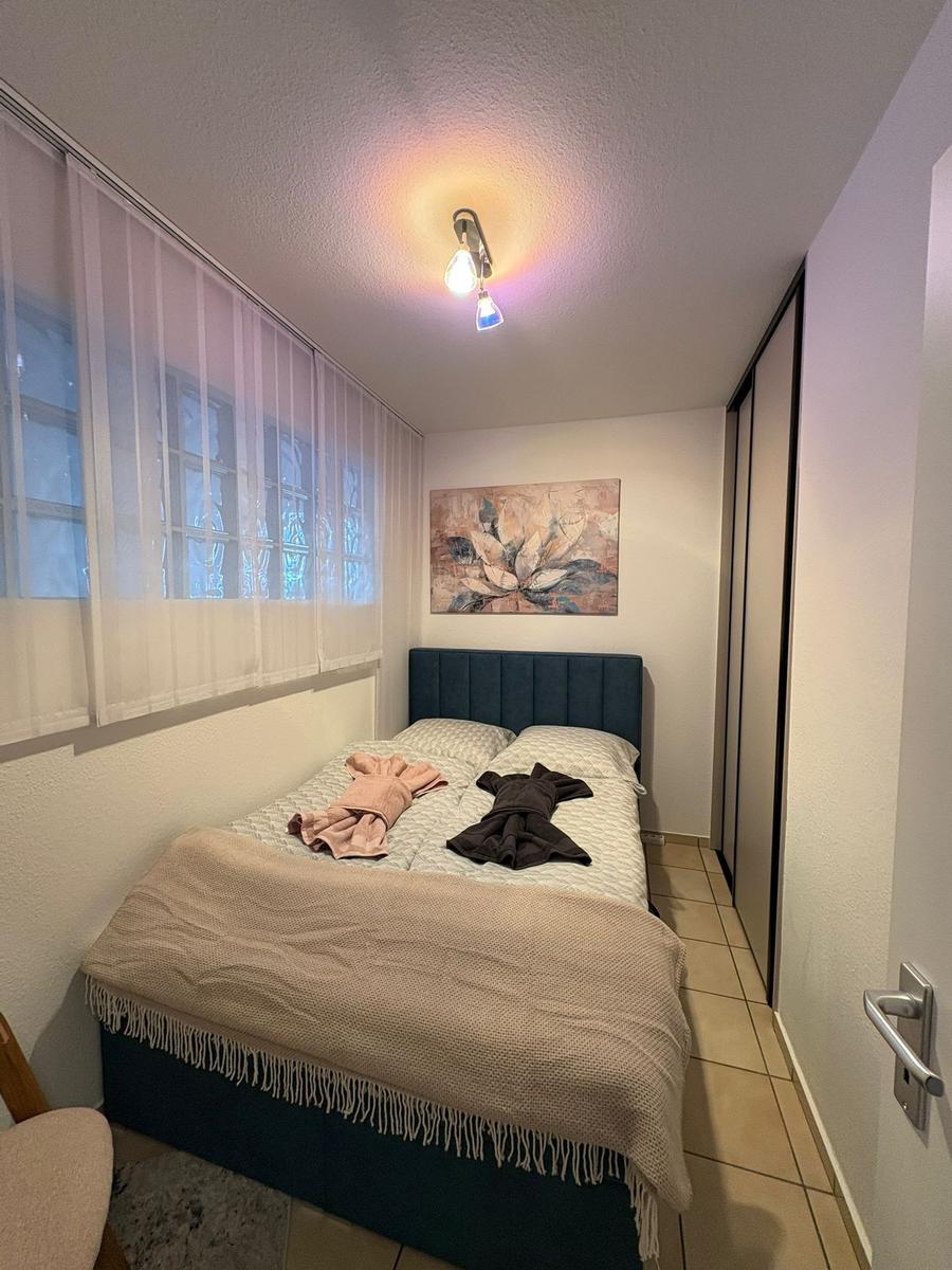 Schlafzimmer mit Bett, Wandbild und Fenster mit Vorhängen.
