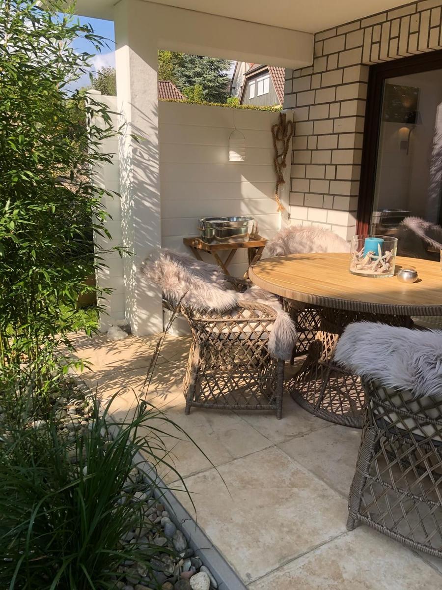 Terrasse mit runden Tisch und Stühlen, belegt mit flauschigen Decken.