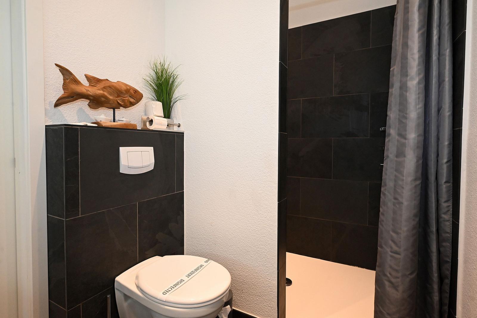 Badezimmer mit Toilette, Dusche und Holzdekoration.