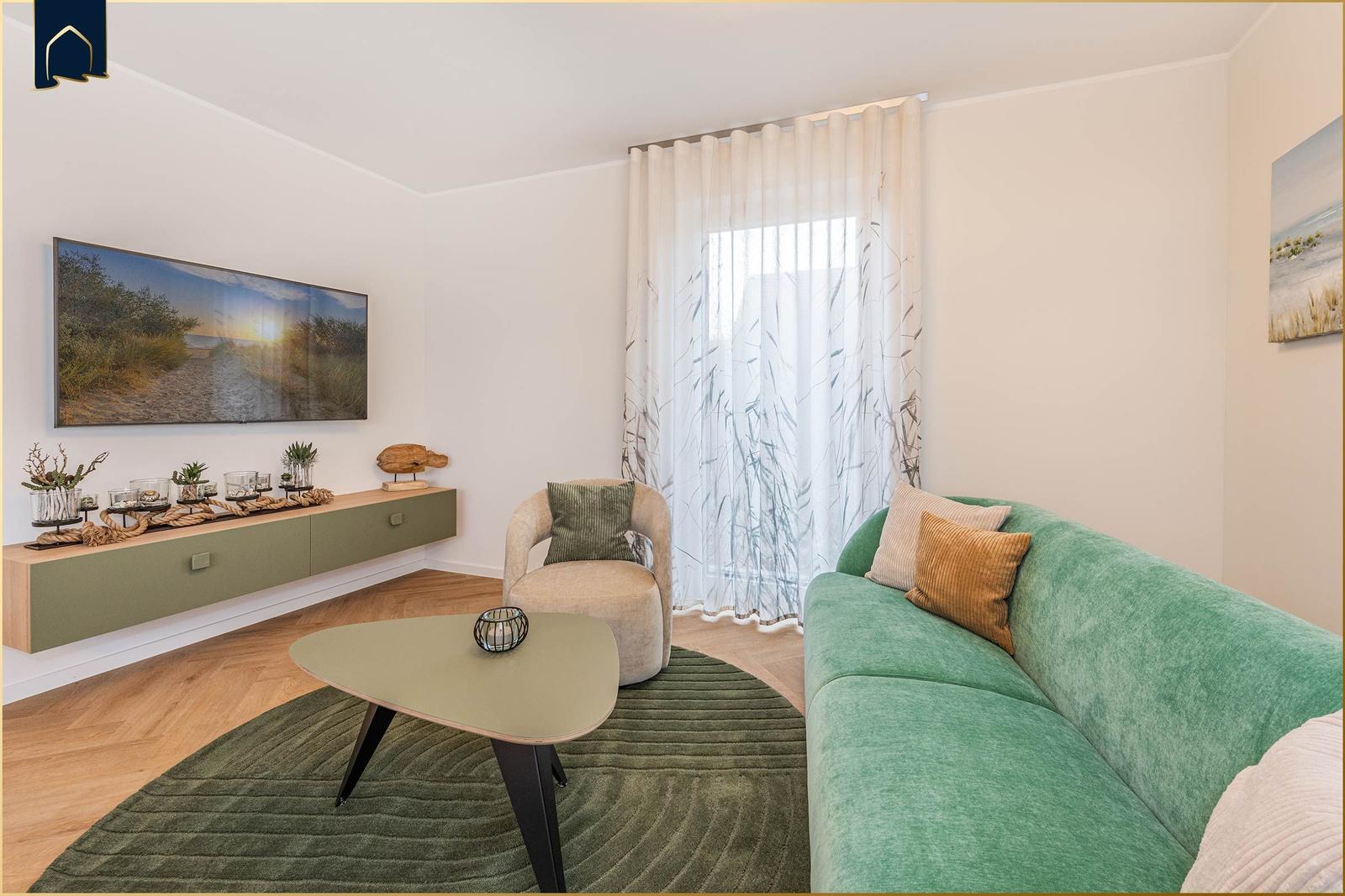 Ein Wohnzimmer mit grünem Sofa, runden Teppich und Wandbild.