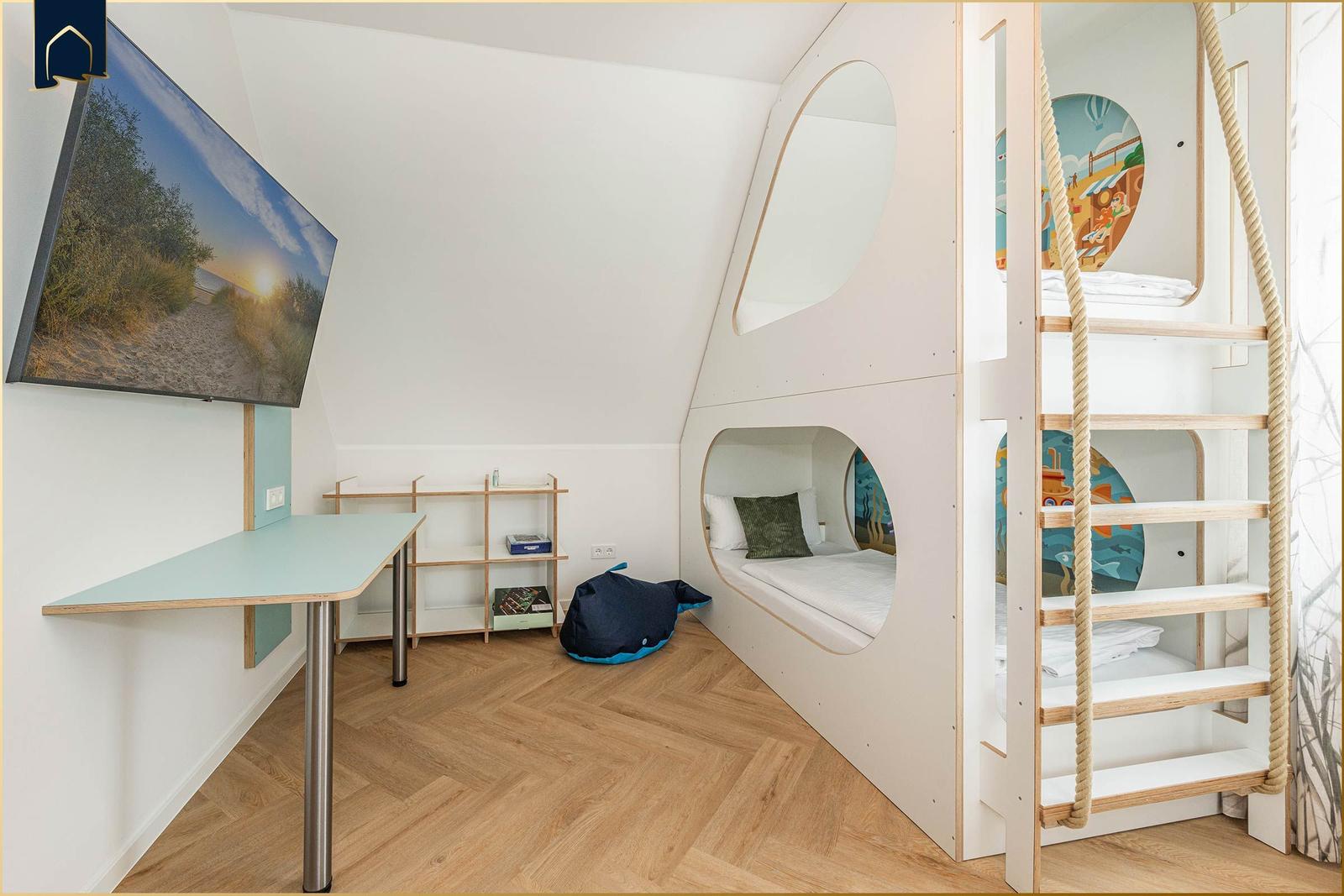 Kinderzimmer mit Kletterturm, Bett und Schreibtisch an der Wand.