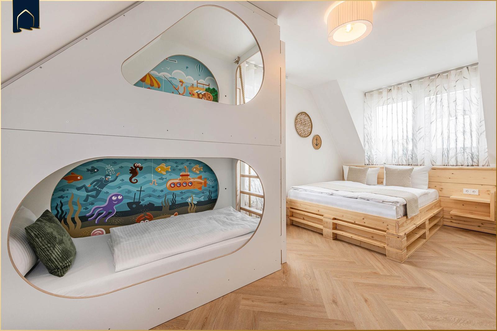 Zimmer mit Kinderbett und Doppelbett, Wandmalereien und Holzboden.