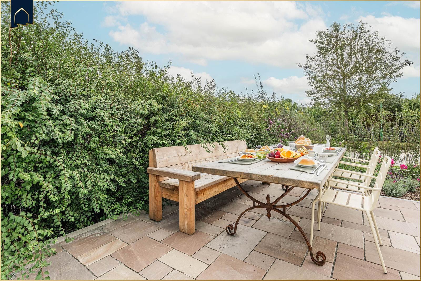 Terrasse mit Holzbank, Tisch und Stühlen. Frühstück auf rustikalem Tisch.