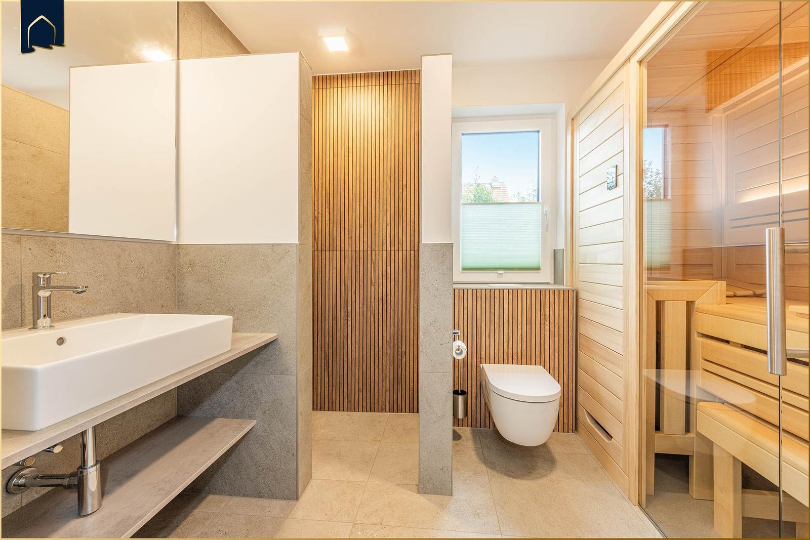 Badezimmer mit Waschbecken, Toilette und Sauna. Holz- und Steinoptik.