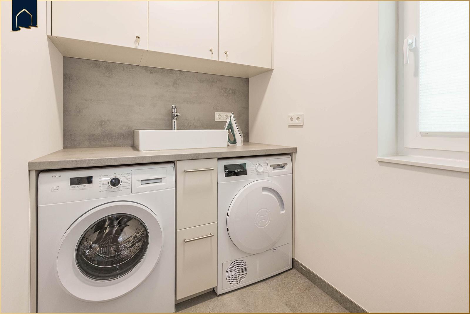 Wäscheschrank mit Waschmaschine und Trockner, Spüle und Fenster.